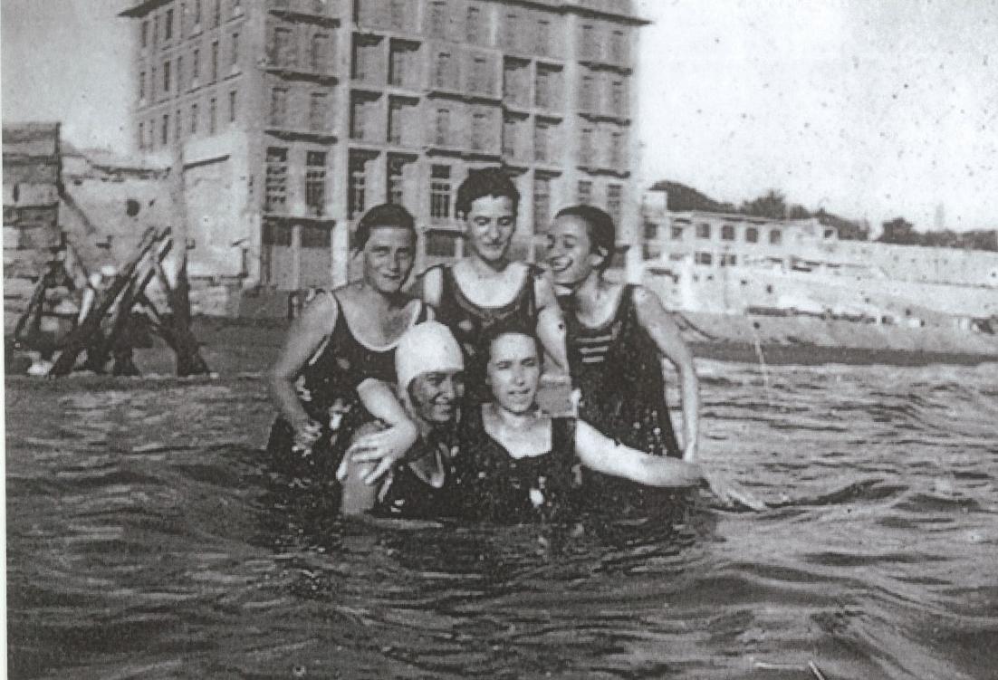 Απεικονίζονται πέντε γυναίκες αγκαλιασμένες μέσα στη θάλασσα