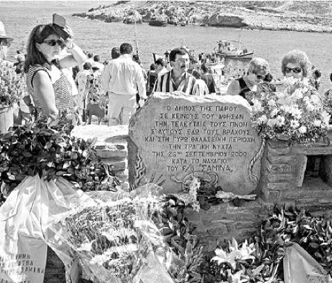 Σε ασπρόμαυρη φωτογραφία απεικονίζεται πλήθος κόσμου, ο τάφος και λουλούδια για τα θύματα του Εξπρές Σαμίνα