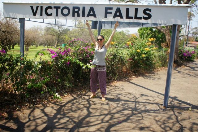 Η Δώρα φωτογραφίζεται κάτω από το πανό που γράφει Victoria Falls