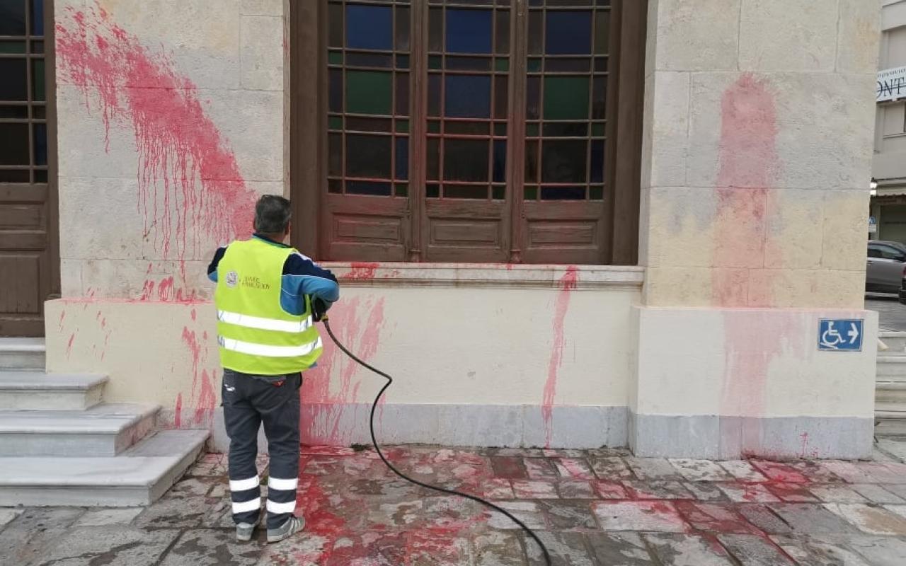 Υπάλληλος του Δήμου καθαρίζει την κόκκινη μπογιά που έριξαν οι βάνδαλοι.