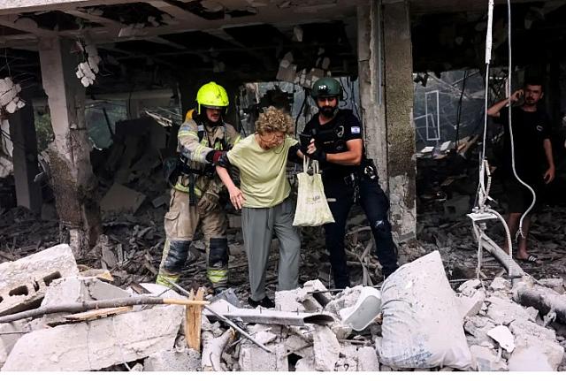 Διασώστες βοηθούν γυναίκα να βγει από τα χαλάσματα κτιρίου στο Τελ Αβίβ / REUTERS/Tomer Appelbaum