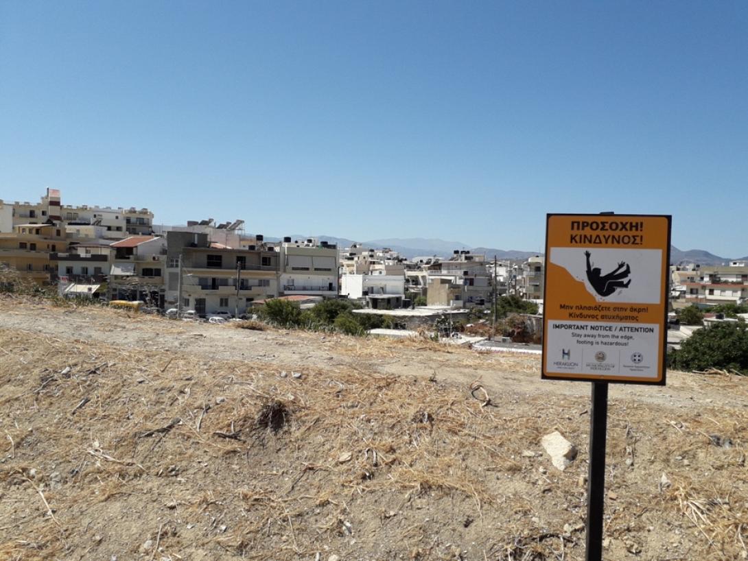 Προειδοποιητική πινακίδα πάνω στα Ενετικά τείχη του Ηρακλείου και μέρος της θέας της πόλης.